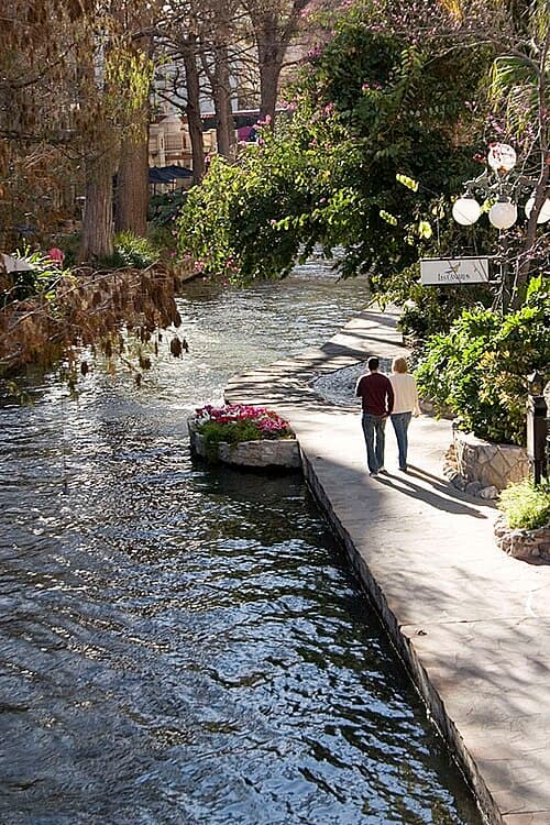 A couple strolls along the Riverwalk by Las Canarias restaurant, at the Omni La Mansion Hotel.