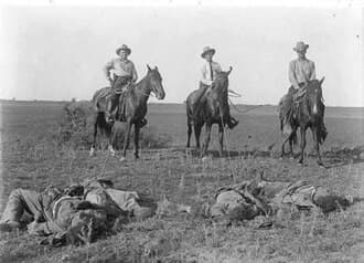 Capt. Monroe Fox and two other Rangers on horseback with their lariats around the bodies of dead Mexicans, after the Norias Ranch Raid August 8, 1915.